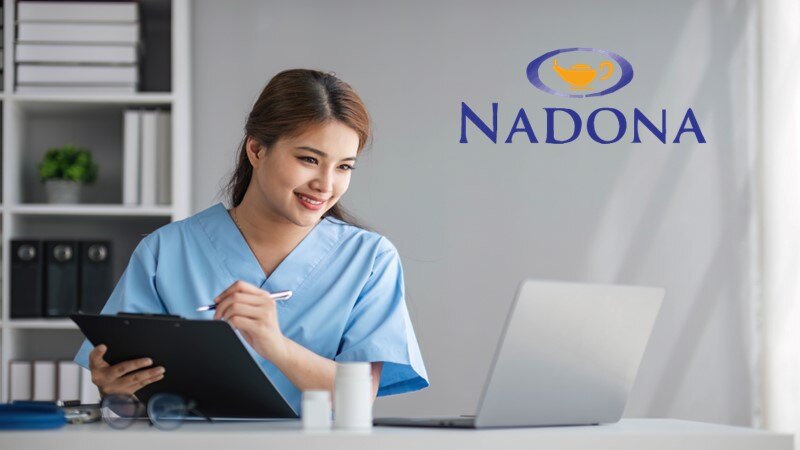 nurse with clipboard smiling at laptop